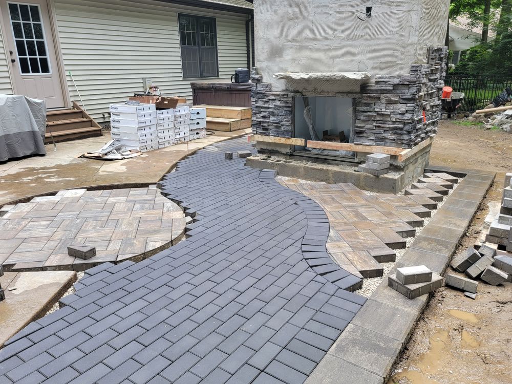 Stone outdoor fireplace with heavy mantel beside a curved paver patio