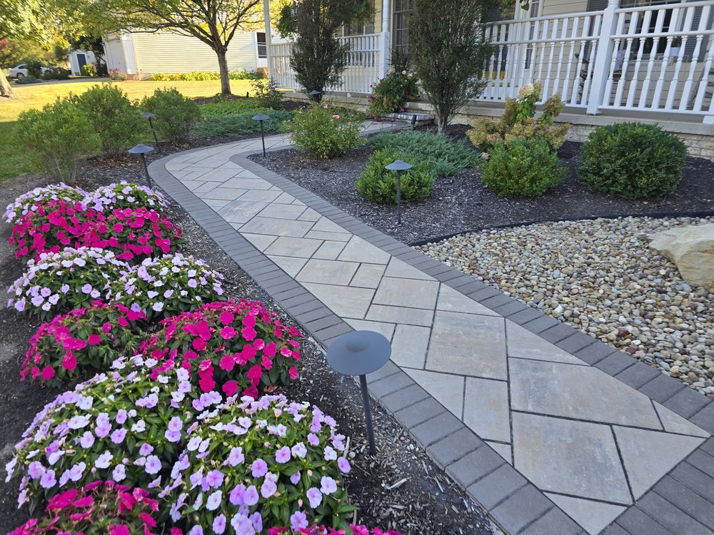 Paver walk with charcoal border curving through beds of impatiens