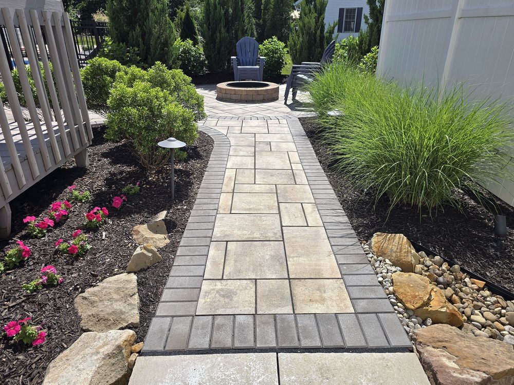 Paver walk between planted beds opening onto a circular fire pit patio