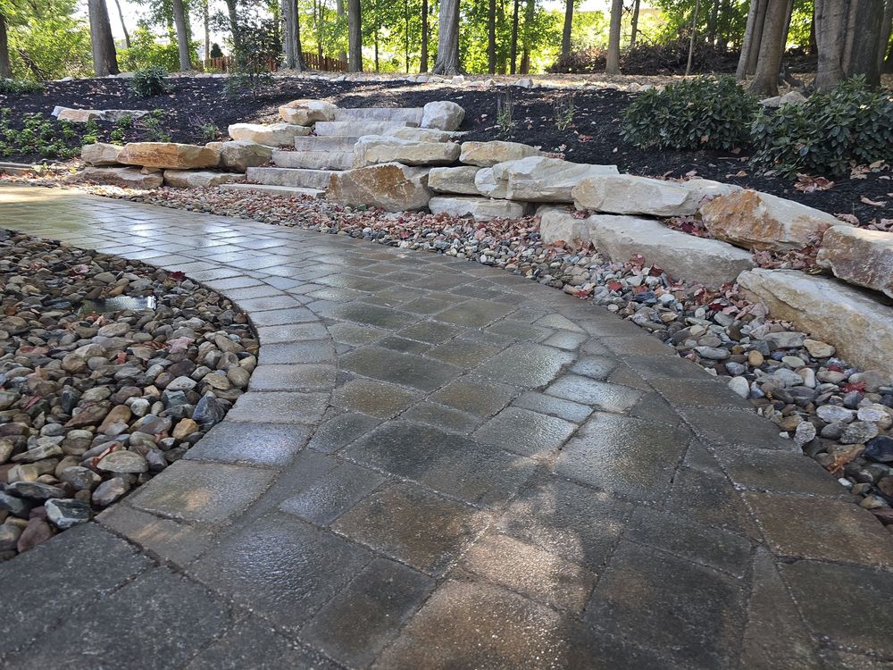 Curved paver walk sweeping between river rock and a boulder outcropping