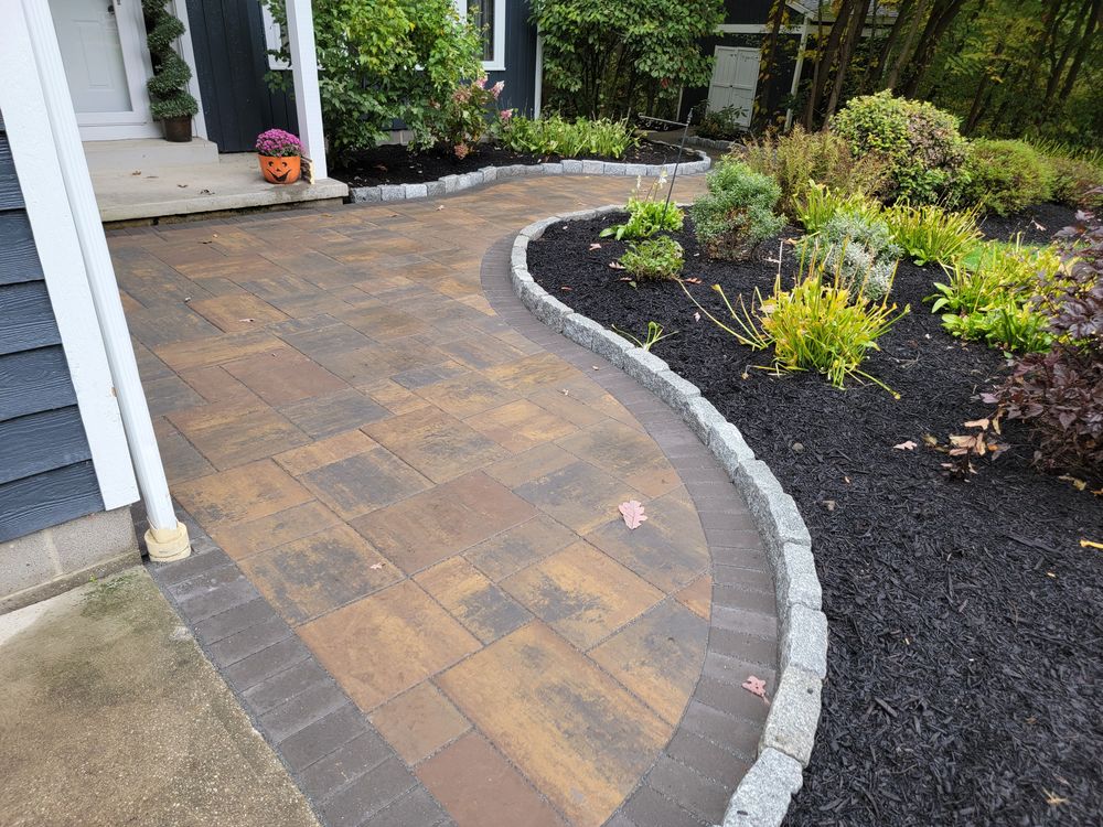 Circular paver patio with blue Adirondack chairs around a fire bowl