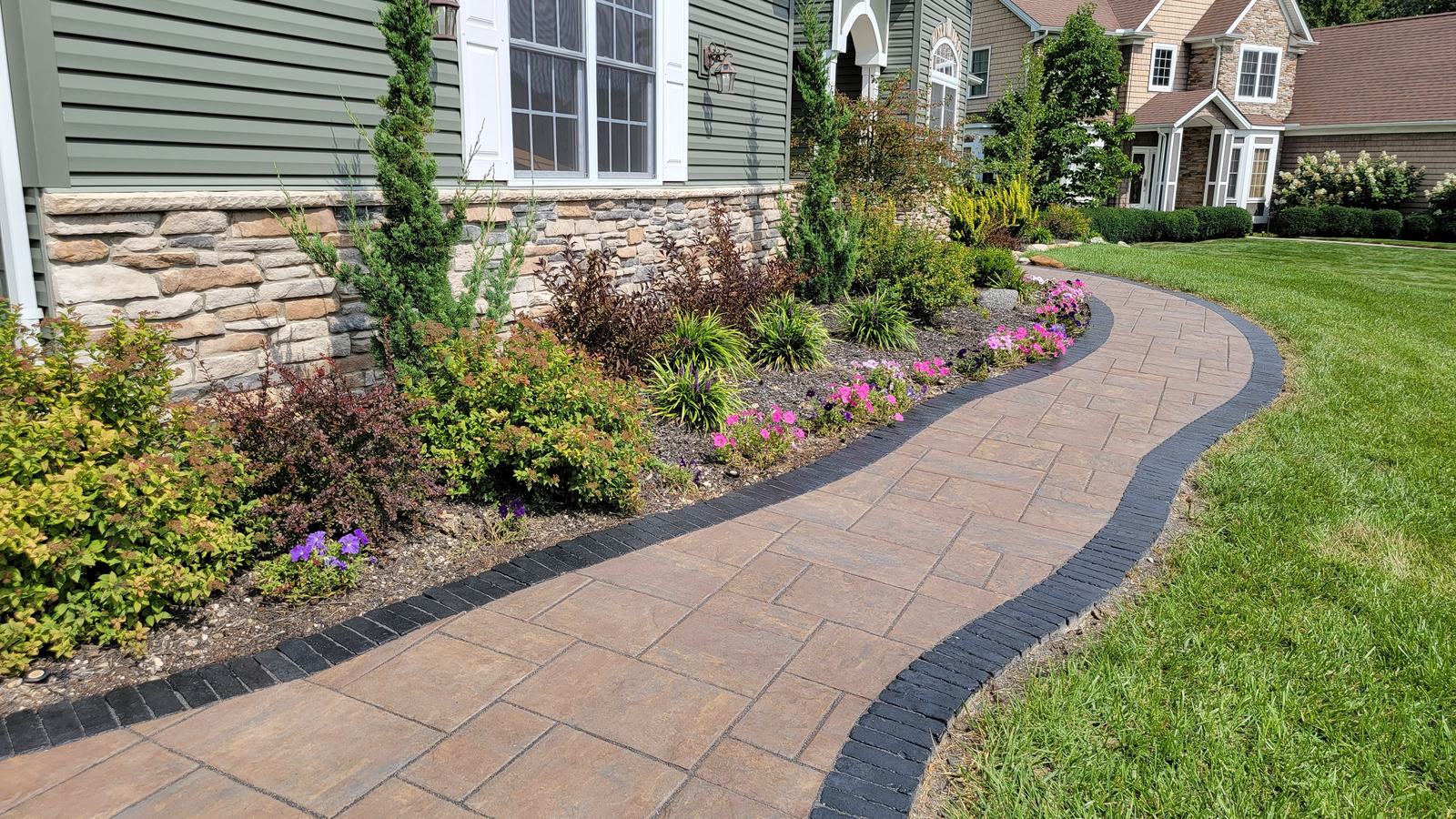 Curved paver walkway with charcoal border and front plantings on a job in Summit County, Ohio