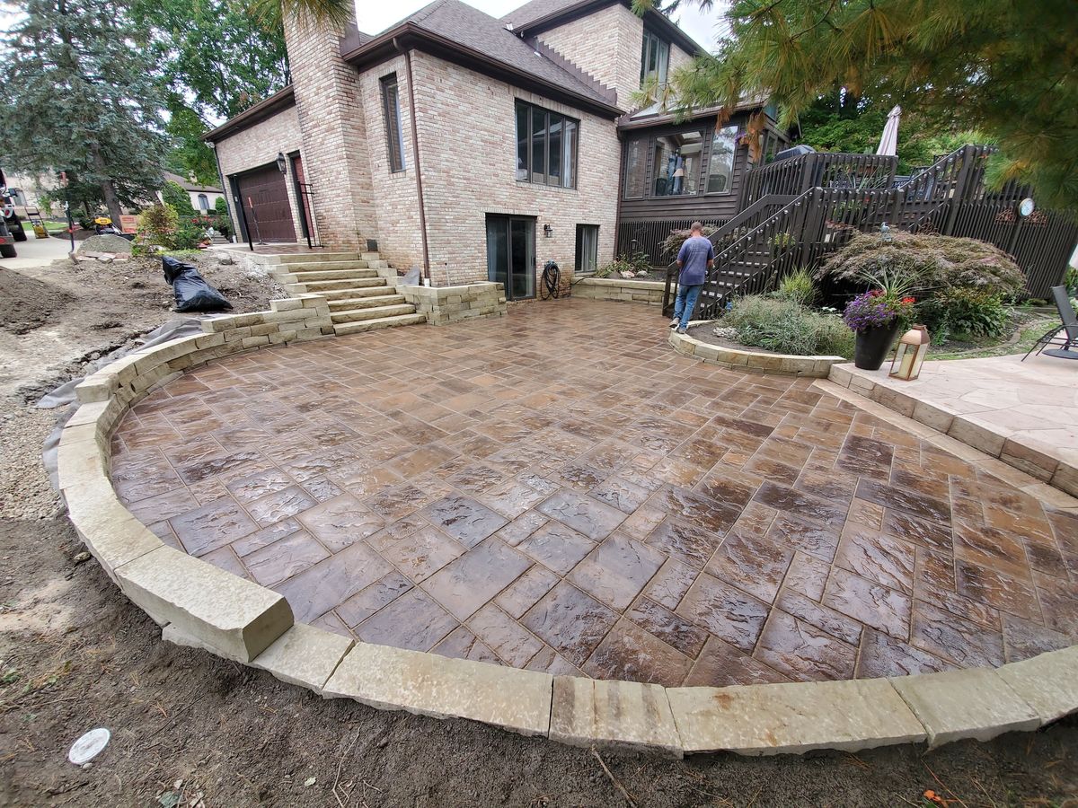 Finished multi-level paver terrace with sandstone seat walls, wide view with the house behind