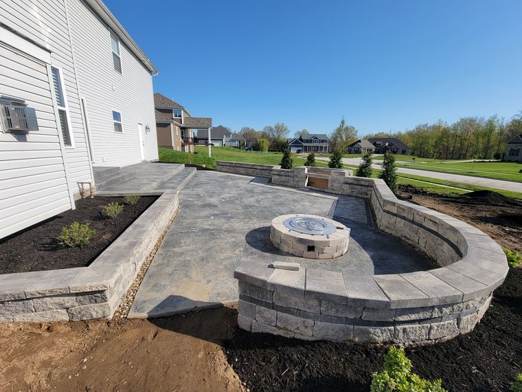 Curved block seat wall wrapping a round gas fire pit with a metal burner insert