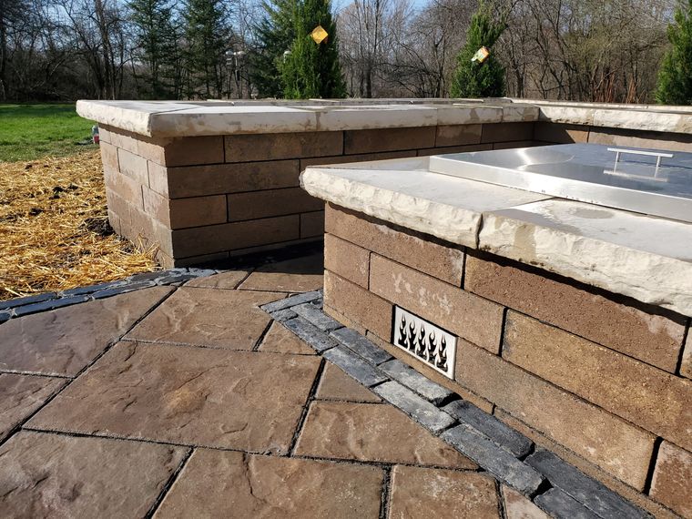 Block grill island with natural stone caps, stainless grill and side burner installed