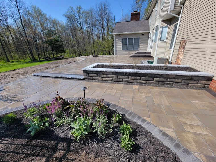 Large paver terrace with a block raised planter bed set into it, planted with salvia