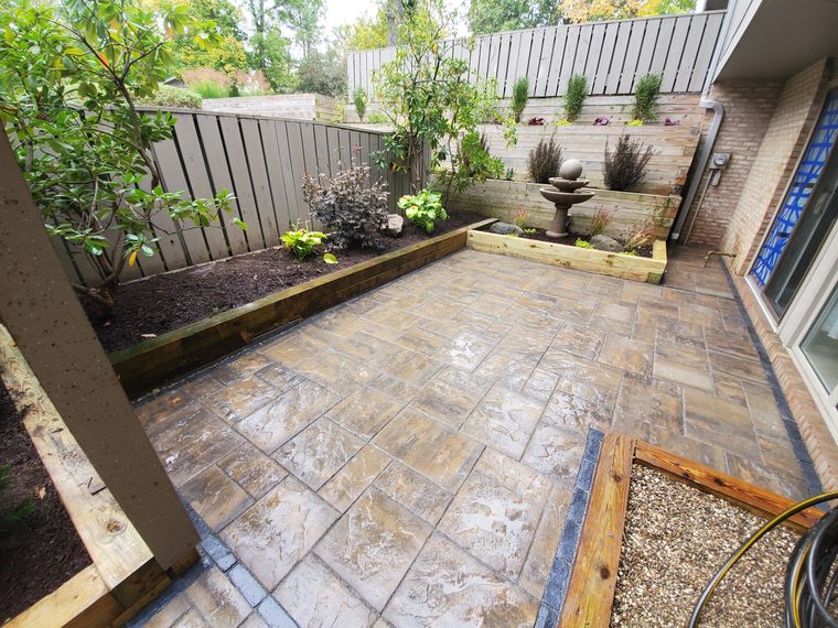 Courtyard with a stone ball fountain set against planted timber raised beds